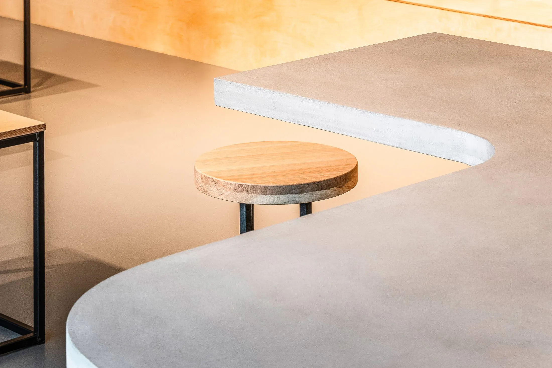 Détail du plan de travail en béton clair et du tabouret rond en bois