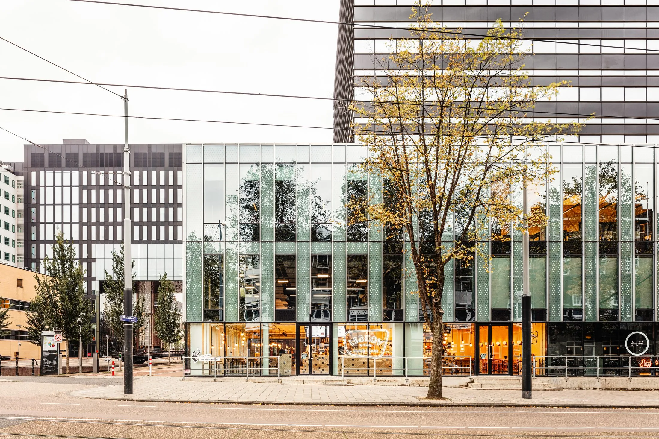 Façade vitrée du bâtiment qui abrite le café, vue depuis la rue