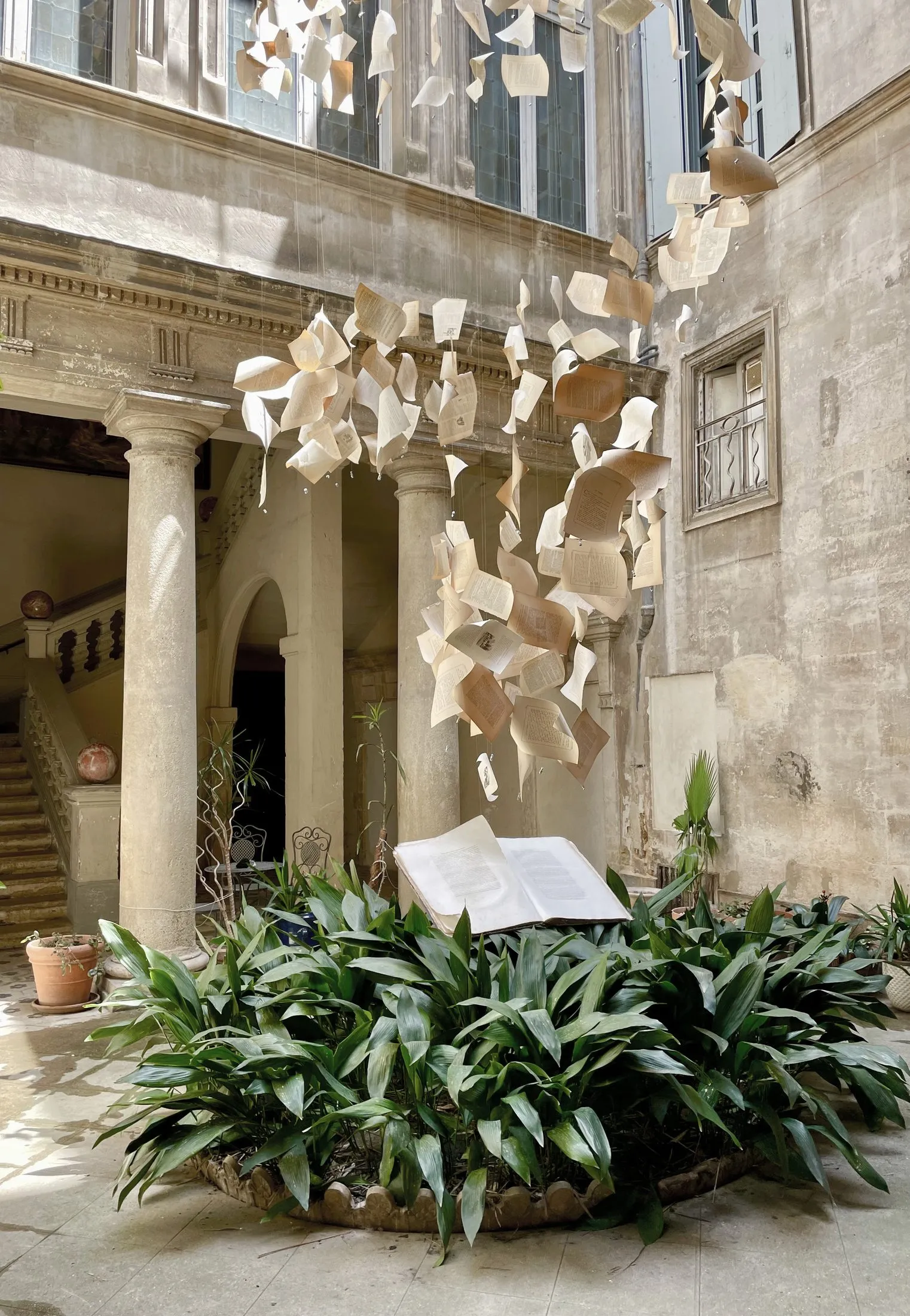 Installation de pages de livre suspendues au-dessus d'un pupitre, dans une cour à colonnades