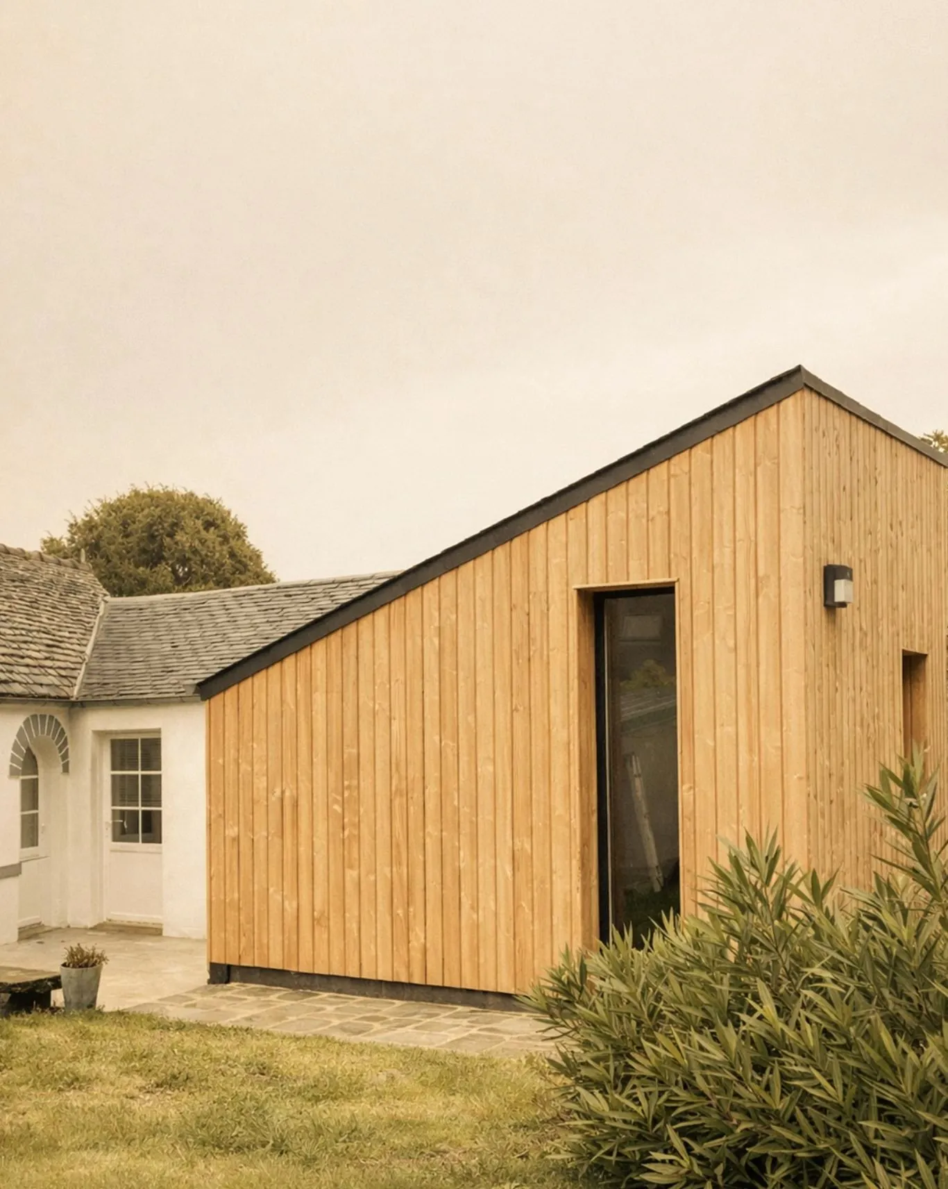 Extension contemporaine en bardage bois clair, accolée à la maison en pierre