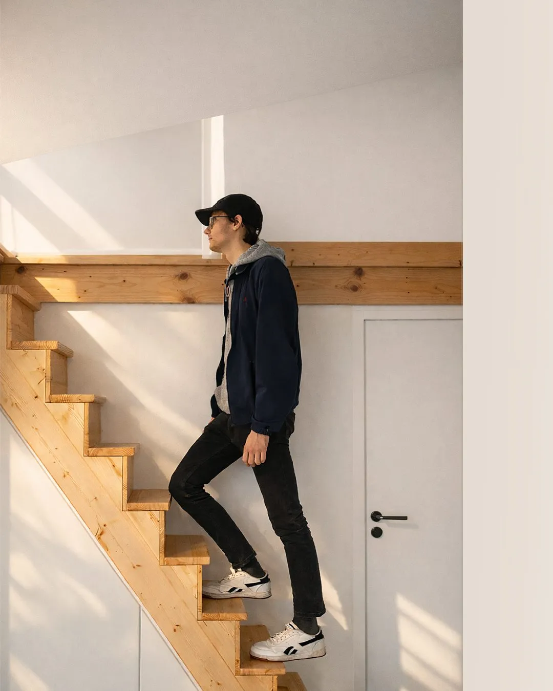 Escalier en bois clair emprunté par une personne, sous une poutre apparente
