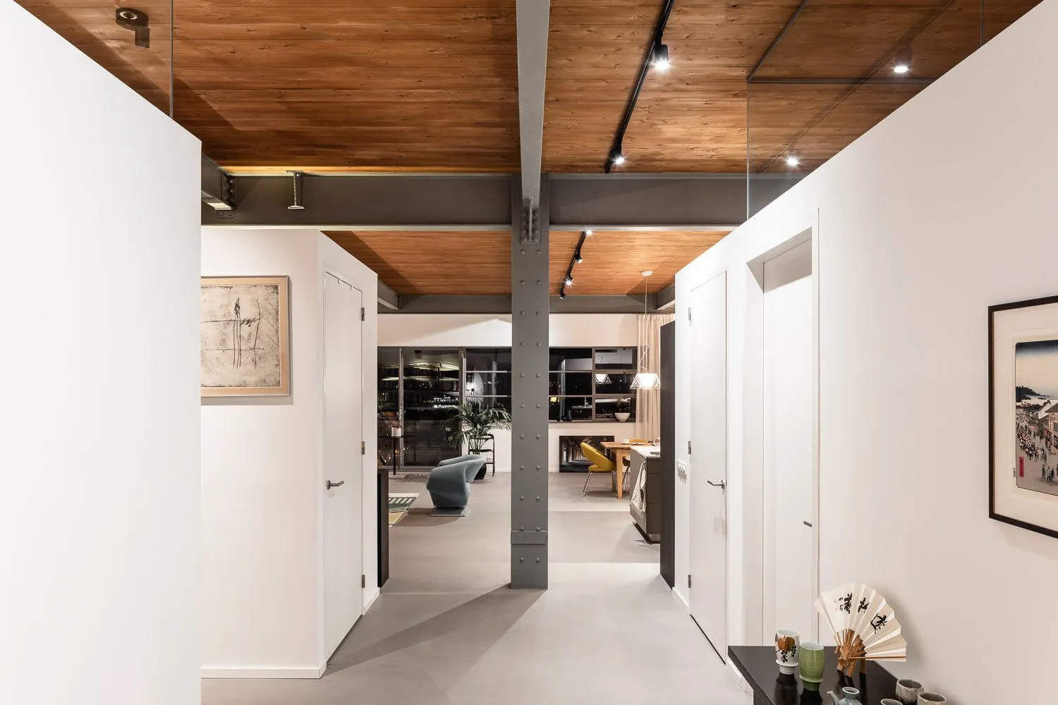 Couloir traversant du loft, poteau métallique et enfilade de portes blanches