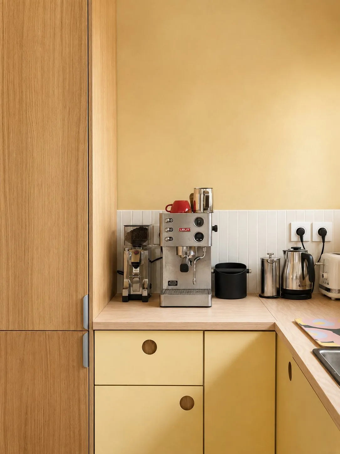 Détail de la cuisine jaune : machine à café sur le plan de travail et rangements en bois
