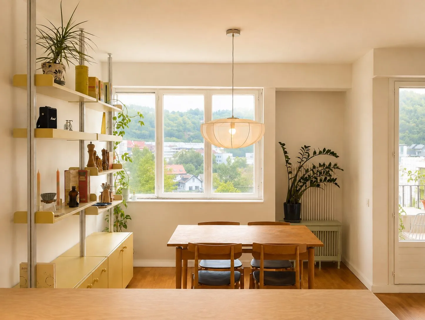Salle à manger, table en bois clair et étagères sur mesure sous une suspension