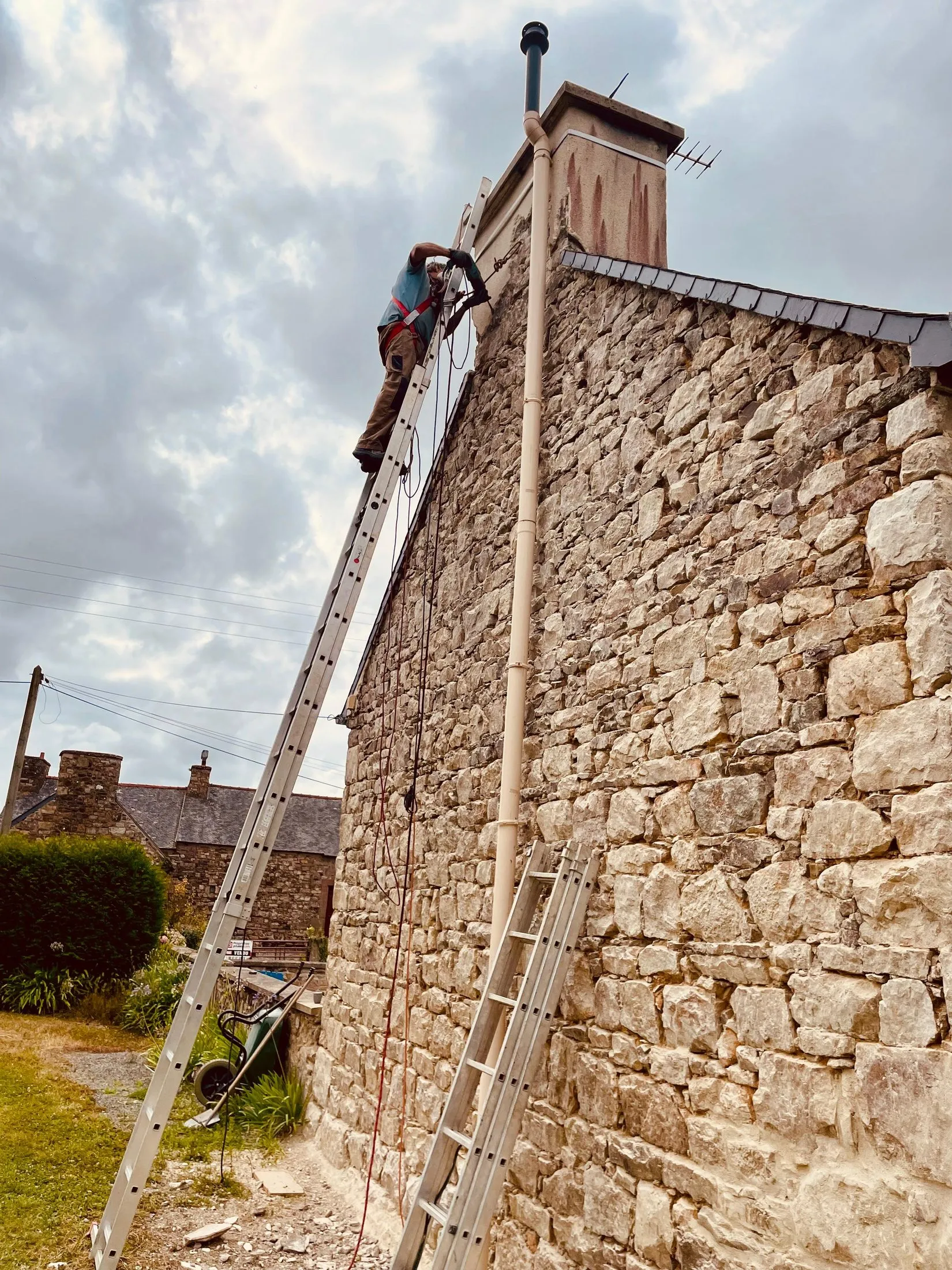 Chantier : échafaudage et échelle dressés contre le pignon en pierre