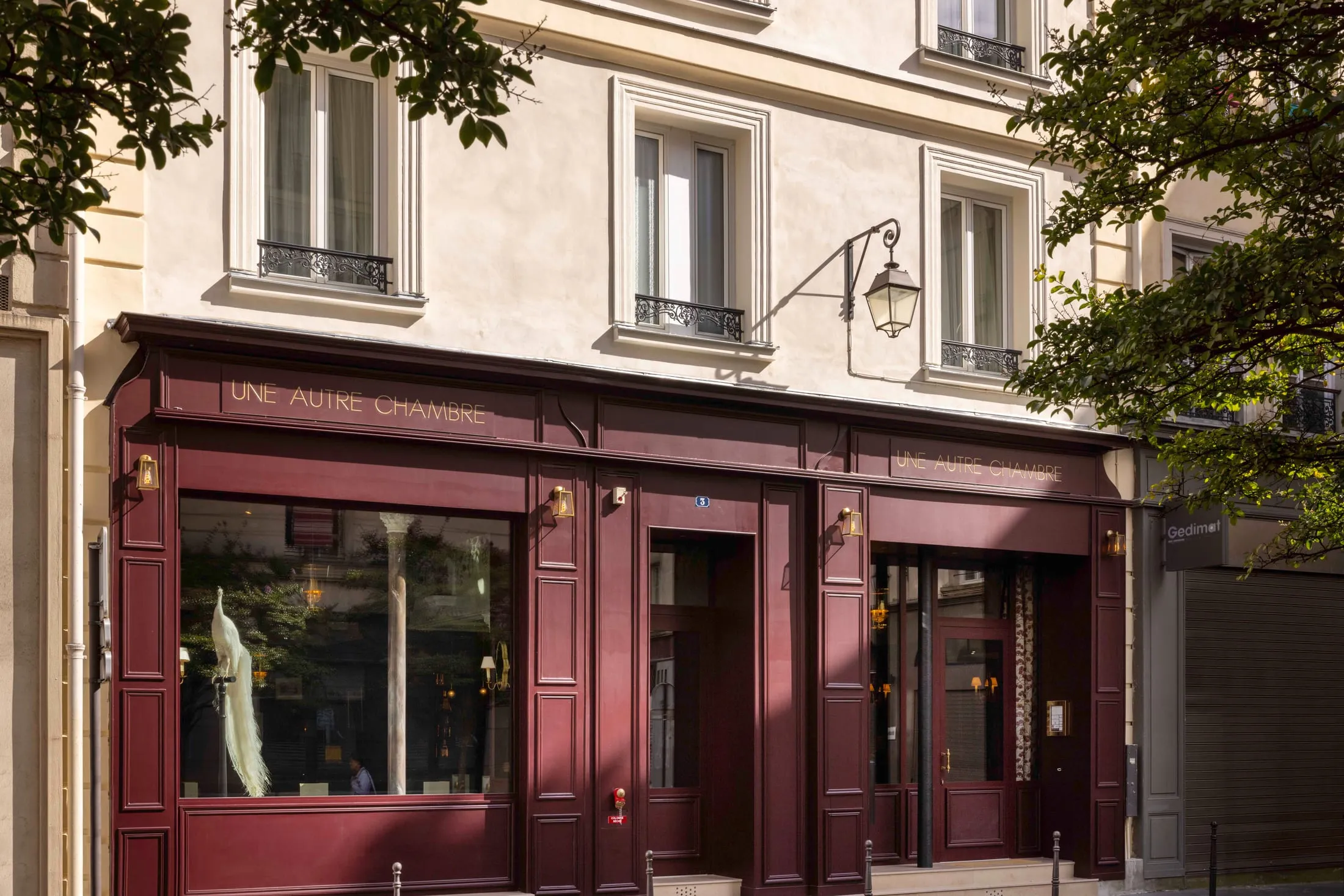 Façade de l'hôtel, devanture bordeaux et enseigne Une autre chambre, dans une rue de Paris